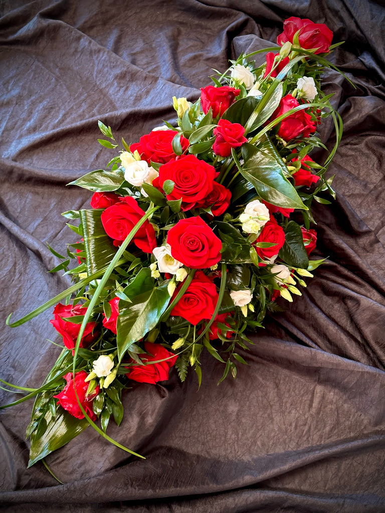 Puna-valkoinen arkkulaite, jossa pääkukkana punainen ruusu. 
