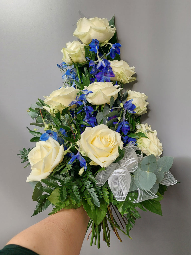 Kukkakimppu hautajaisiin. Valkoista ruusua ja sinistä ritarinkannusta.