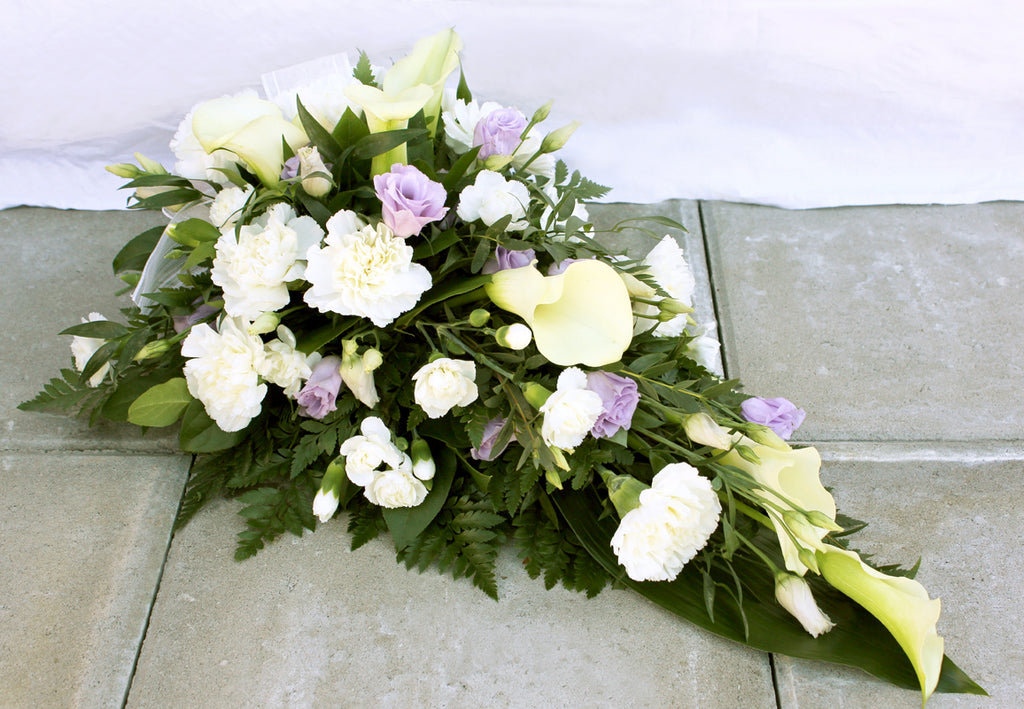 Kukkalaite hautajaisiin. Valkoista kallaa ja neilikkaa, valkoista ja vaaleanviolettia eustomaa.