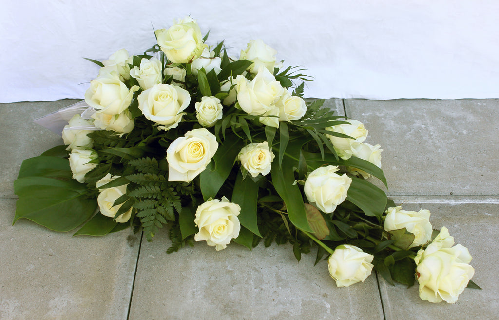 Kukkalaite hautajaisiin. Valkoista ruusua ja leikkovihreitä.