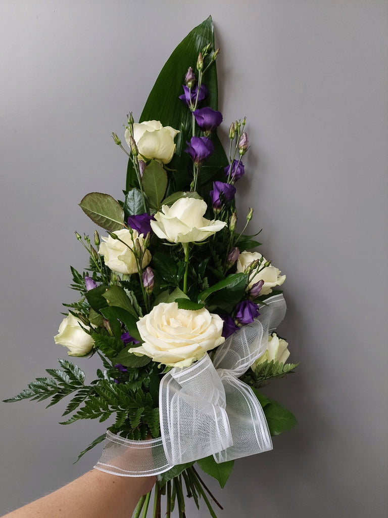 Kukkakimppu hautajaisiin. Valkoista ruusua ja violettia eustomaa.