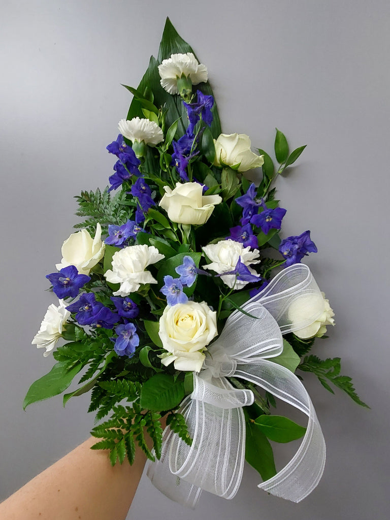 Kukkakimppu hautajaisiin. Valkoista ruusua ja sinistä ritarinkannusta.