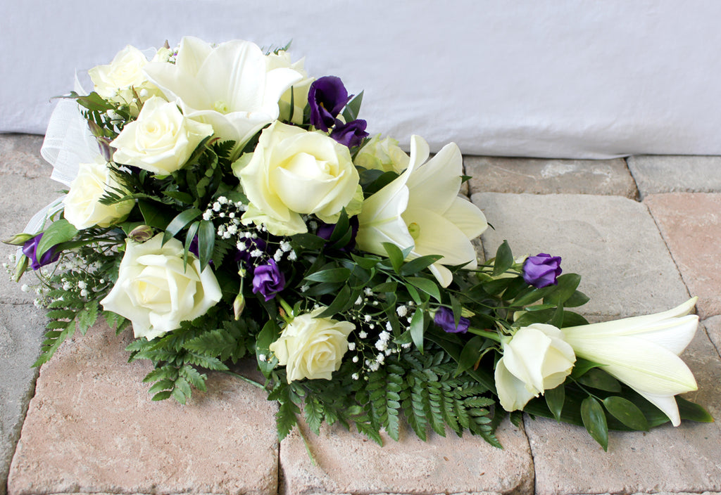 Kukkalaite hautajaisiin. Valkoliljaa, valkoista ruusua ja violettia eustomaa.