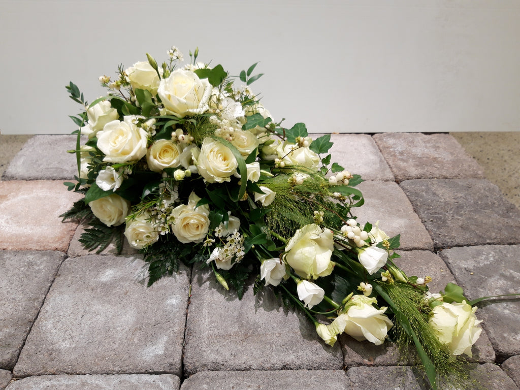 Kukkalaite hautajaisiin. Runsaasti valkoista ruusua ja eustomaa, sekä leikkovihreitä.